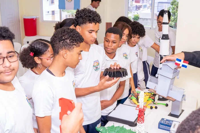 Prado Oriental School students examine a 3D-printed piece next to the tower, a robot and the Saturn V rocket