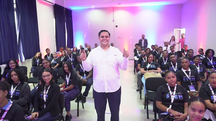Jean Frías smiles with two thumbs up among students of INDOTEL’s STEM Student Merit Award at UCNE